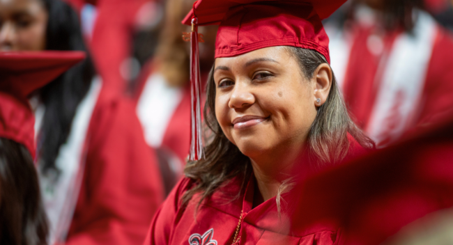 Online RN to BSN graduate smiles at graduation, wearing her red UL Lafayette cap and gown.